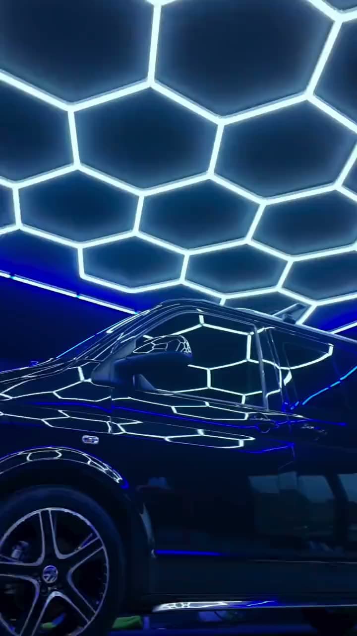 A black VW Transporter in the DRIP'D bay with the hex ceiling lights reflected down its side